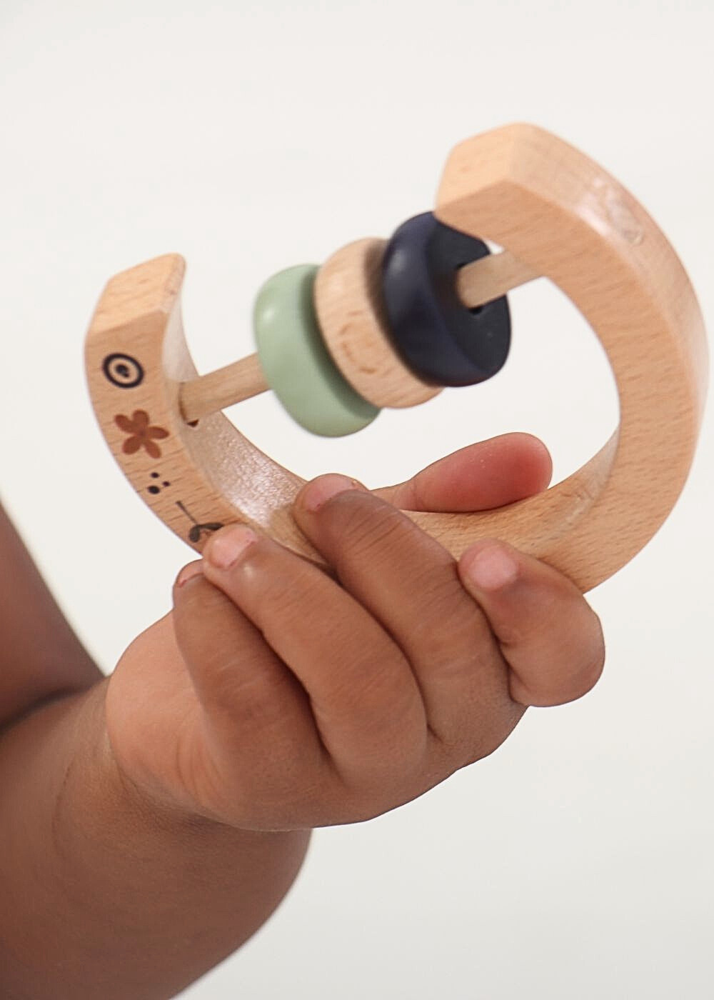 Wooden Baby Rattle being held by a baby, featuring colourful rings for teething and gripping.