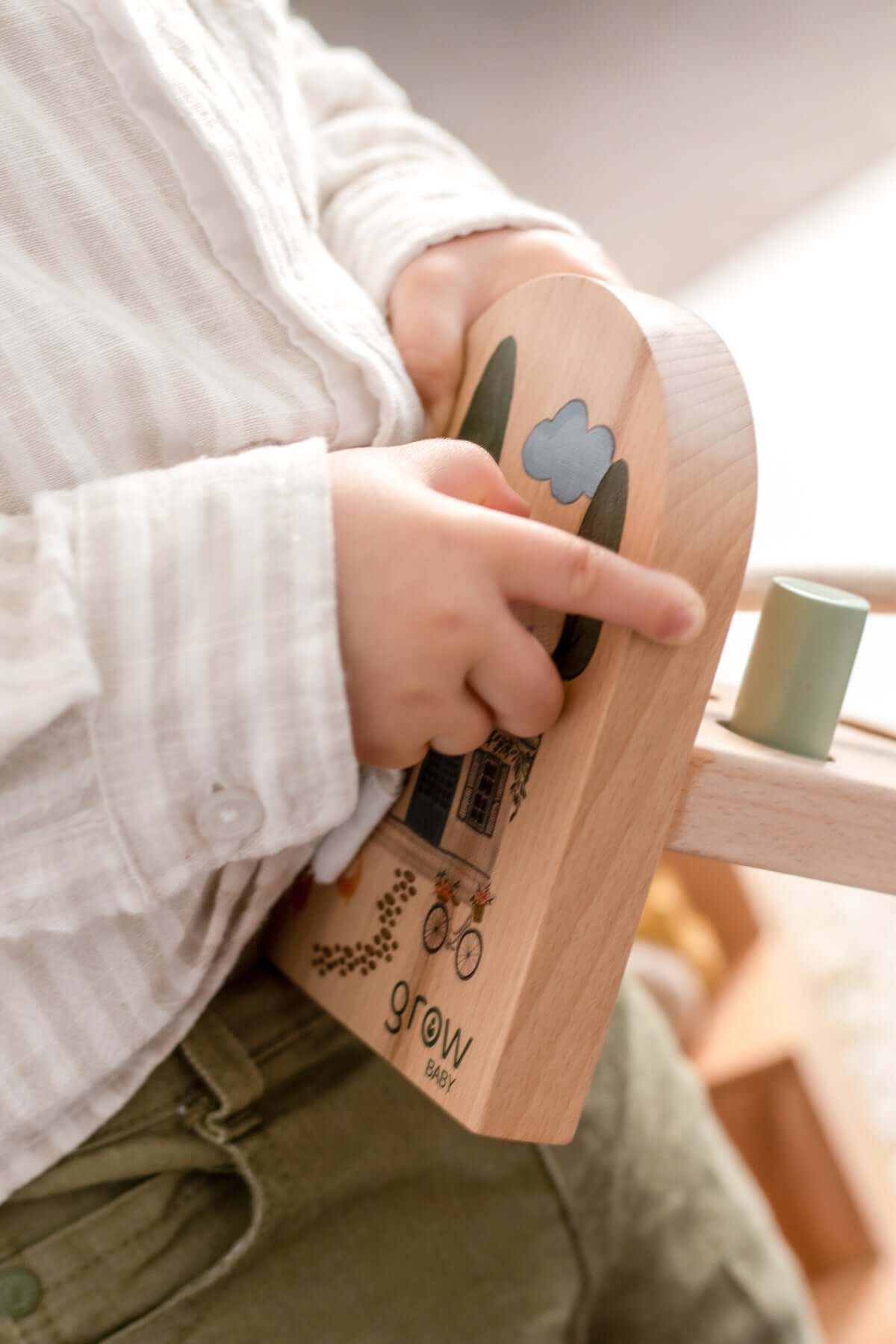Child playing with a wooden toy from the Little Greyton Collection, showcasing imaginative design and charm.