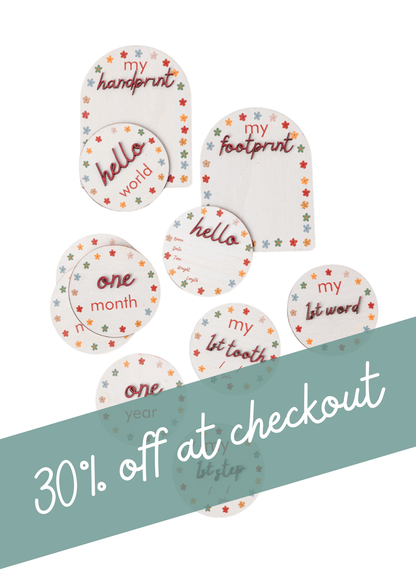 Wooden Baby Milestone Disc gift set with colorful printed milestones, including hello, handprint, and one month