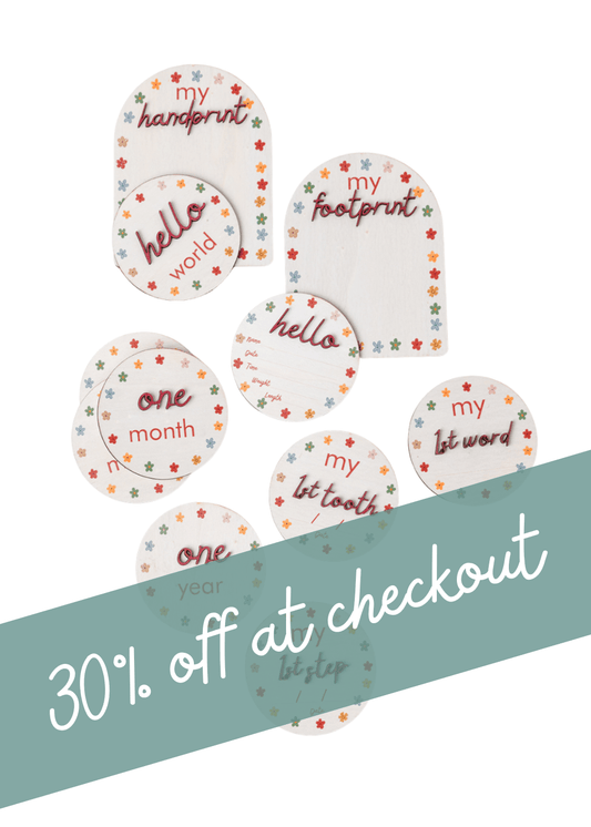 Wooden Baby Milestone Disc gift set with colorful printed milestones, including hello, handprint, and one month