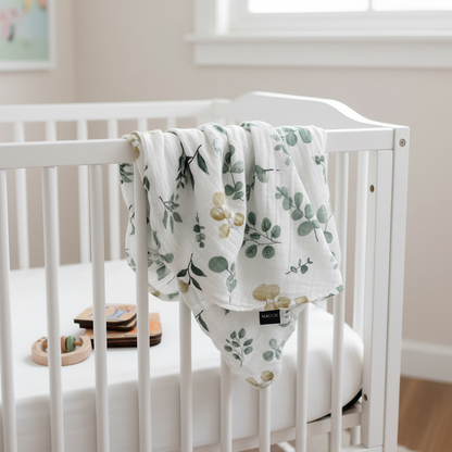 Baby Gift Set featuring Maccie Swaddle hanging over a crib, showcasing natural floral patterns.