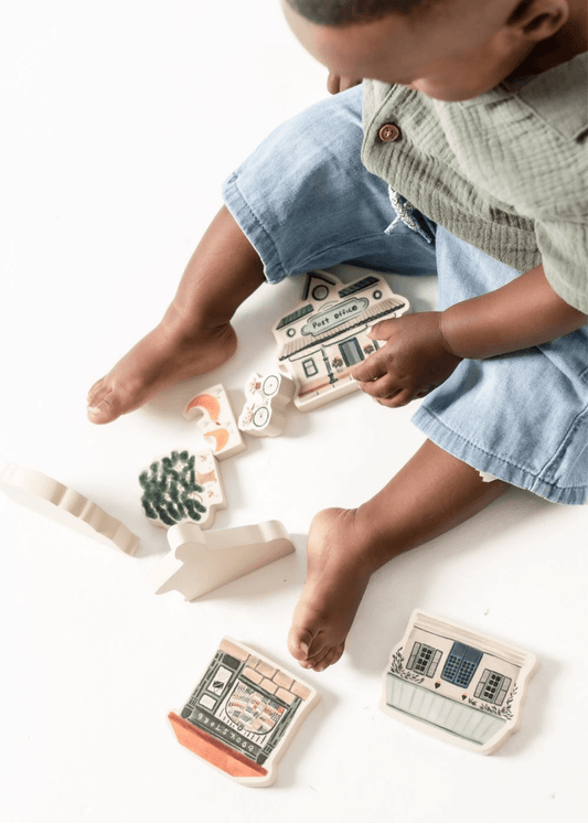 Child playing with Wooden Play Set pieces on the floor, exploring creative building and imaginative play.
