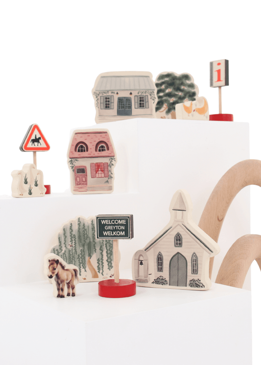 Wooden toy play set featuring charming village pieces, nature items, and a welcome sign for imaginative play.