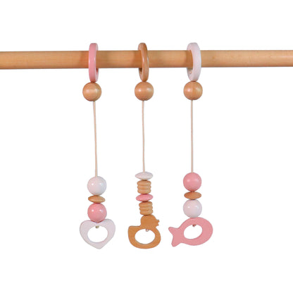 Wooden baby gym accessories featuring pastel pink and natural wood hanging toys.