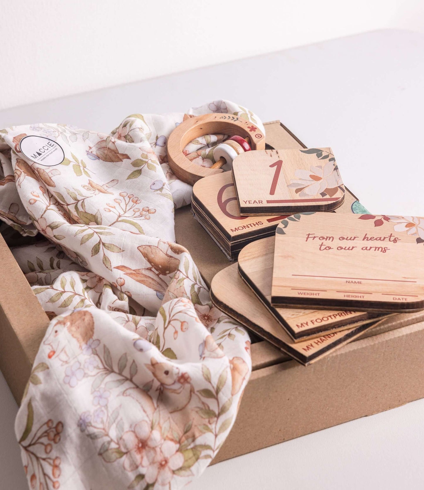 Baby Gift Set featuring Maccie swaddle, milestone disks, and rattle beautifully arranged in a gift box.