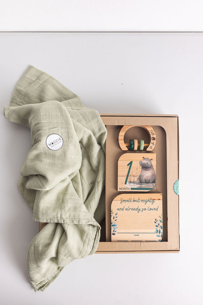 Baby Gift Set featuring Maccie Swaddle, milestone disk, and rattle on a light background.