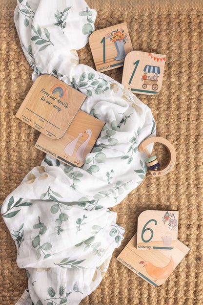 Baby Gift Set featuring Maccie Swaddle, milestone disks, and rattle on a textured backdrop.